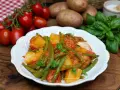 Un piatto di fagiolini e patate alla pugliese, con pomodorini freschi e basilico, pronto per essere gustato.