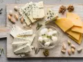 Assortimento di formaggi freschi: mozzarelline, feta e formaggi stagionati, con noci e pistacchi.