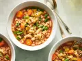 Tre ciotole di fumante pasta e fagioli vegetariana, ricca di verdure e condita con parmigiano.
