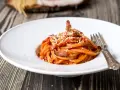 Piatto di spaghetti con sugo rosso, guanciale e formaggio grattugiato. Una gustosa ricetta originale amatriciana cipolla.