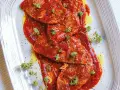 Bistecche alla pizzaiola succulente, ricoperte da salsa rossa e guarnite con erbe aromatiche fresche.