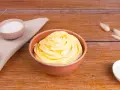 Crema al burro ricetta della nonna, soffice e profumata, pronta per decorare torte. Zucchero e ingredienti in vista.