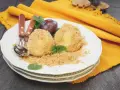Due deliziosi gnocchi di susine, ricoperti di pangrattato e guarniti con menta, su un piatto bianco con posate.