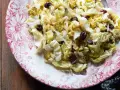 Deliziosa insalata di verza con uvetta, servita su un piatto decorato con fiori rossi.