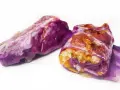 Due involtini di cavolo cappuccio viola, ripieni di riso e verdure, su sfondo bianco.
