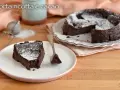 Una fetta di torta ricotta e cioccolato senza farina, cosparsa di zucchero a velo, su un piatto bianco.