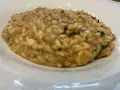 Un cremoso risotto alla pescatora ricetta napoletana, con riso carnaroli e profumi di mare, servito in un piatto bianco.