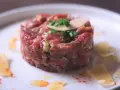 Tartare di manzo, un piatto raffinato. Scopri come condirla per un sapore indimenticabile, con scaglie di parmigiano e un tocco di paprika.