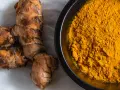 Radici di curcuma e polvere dorata in una ciotola, perfette per dare colore e sapore alla pasta.