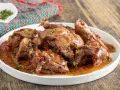 Piatto di coniglio con peperoni rossi e verdi, cotto in umido con erbe aromatiche.