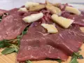 Carne salada cos'è? Fettine sottili di carne rossa, condite con erbe aromatiche e scaglie di formaggio stagionato, su un letto di rucola fresca.