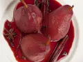 Pere cotte nel vino, profumate con cannella, anice stellato e chiodi di garofano, servite in una ciotola bianca.