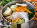 Brodo di pollo in pentola a pressione con carote, cipolla, sedano e prezzemolo.