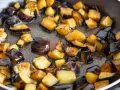 Melanzane a cubetti dorate e caramellate in padella, pronte per uno dei 100 modi per cucinare le melanzane.