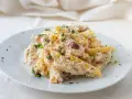 Piatto di pasta cremosa con tonno, capperi e olive taggiasche, guarnito con prezzemolo fresco.