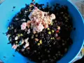 Un'insalata di riso nero con tonno, piselli e cubetti di pomodoro. La cottura del riso nero è perfetta, ogni chicco è ben separato.
