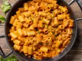 Un invitante piatto di pasta con salsiccia alla napoletana, condita con una cremosa salsa arancione e prezzemolo fresco.