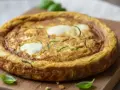 Frittata con mozzarella al forno, dorata e soffice, con zucchine a rondelle e ciuffi di mozzarella filante. Un piatto gustoso e leggero.