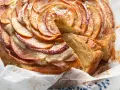Una fetta di torta di mele e yogurt soffice, con mele a spirale e spolverata di cannella.