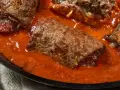 Involtini di carne in padella con sughetto rosso, un piatto succulento e invitante.