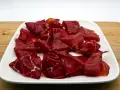 Fette di bresaola, la bresaola che carne è, su un piatto bianco.
