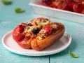 Peperoni ripieni, un classico delle ricette con peperoni, con un gustoso ripieno di pomodoro, olive e pangrattato, guarniti con basilico fresco.