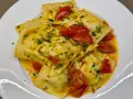 Deliziosi ravioli di pesce conditi con pomodorini e prezzemolo, in un sugo dorato.