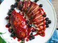 Petto d'anatra ricette: succulento petto d'anatra affettato, glassato con salsa ai frutti di bosco e guarnito con mirtilli freschi.