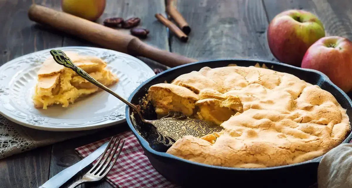 Torta di mele in padella in 10 minuti: soffice e dorata, pronta per essere gustata. Una fetta invitante su un piatto bianco.