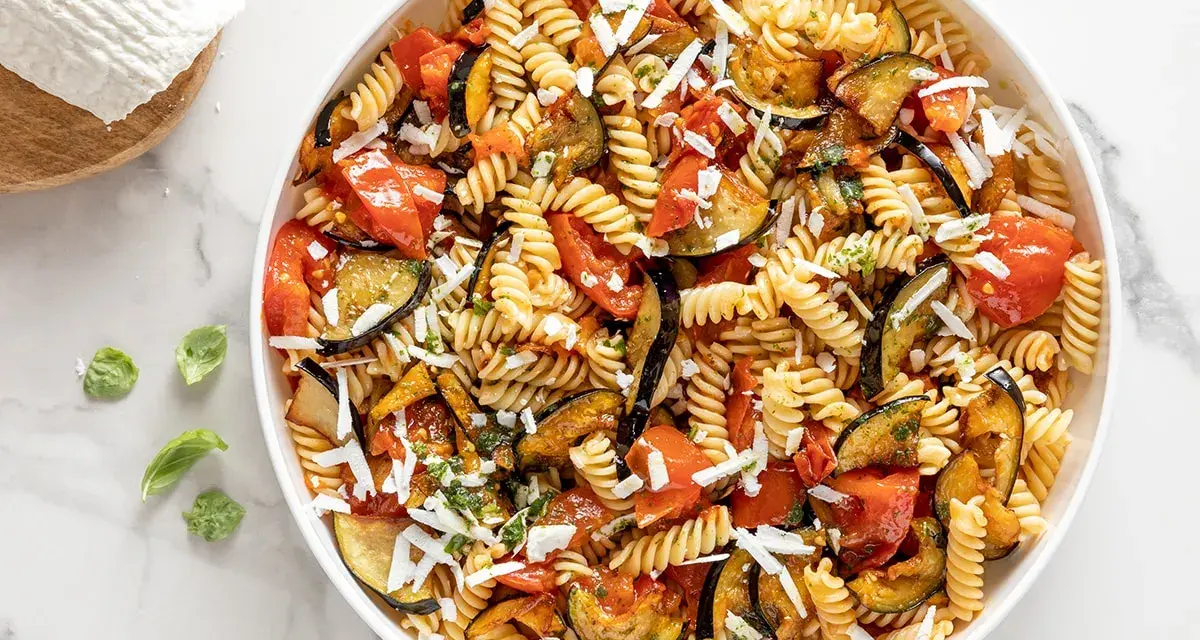 Pasta fredda con melanzane, pomodori e ricotta salata grattugiata. Un'idea perfetta per cosa mettere nella pasta fredda, fresca e saporita.