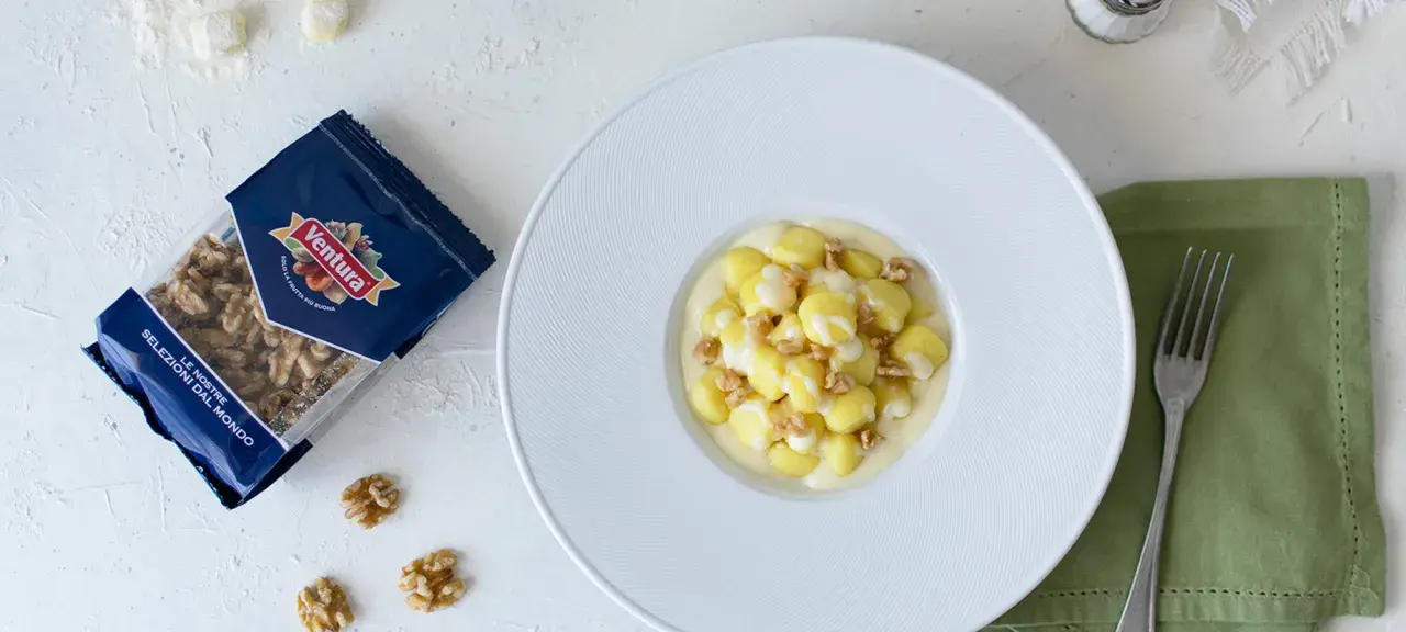Gnocchi al Castelmagno con noci croccanti, un piatto cremoso e saporito. La confezione di noci Ventura accanto promette un tocco di gusto in più.