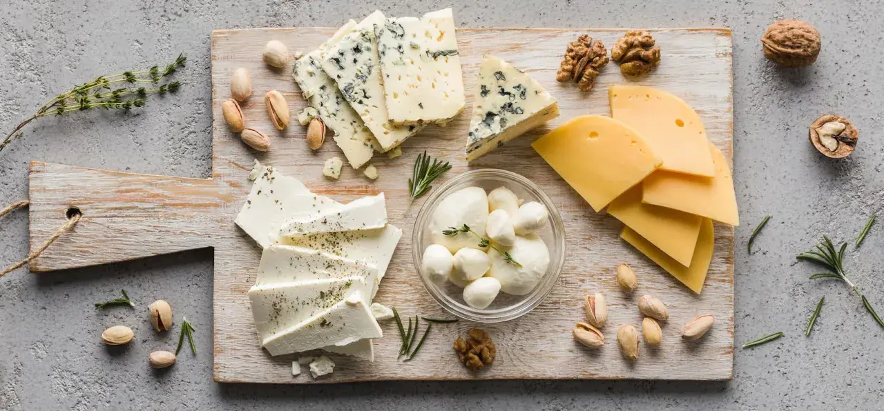 Assortimento di formaggi freschi: mozzarelline, feta e formaggi stagionati, con noci e pistacchi.