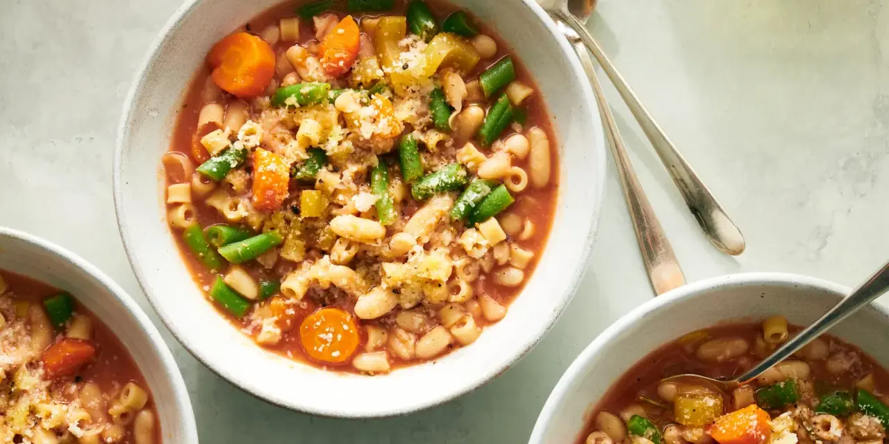 Tre ciotole di fumante pasta e fagioli vegetariana, ricca di verdure e condita con parmigiano.