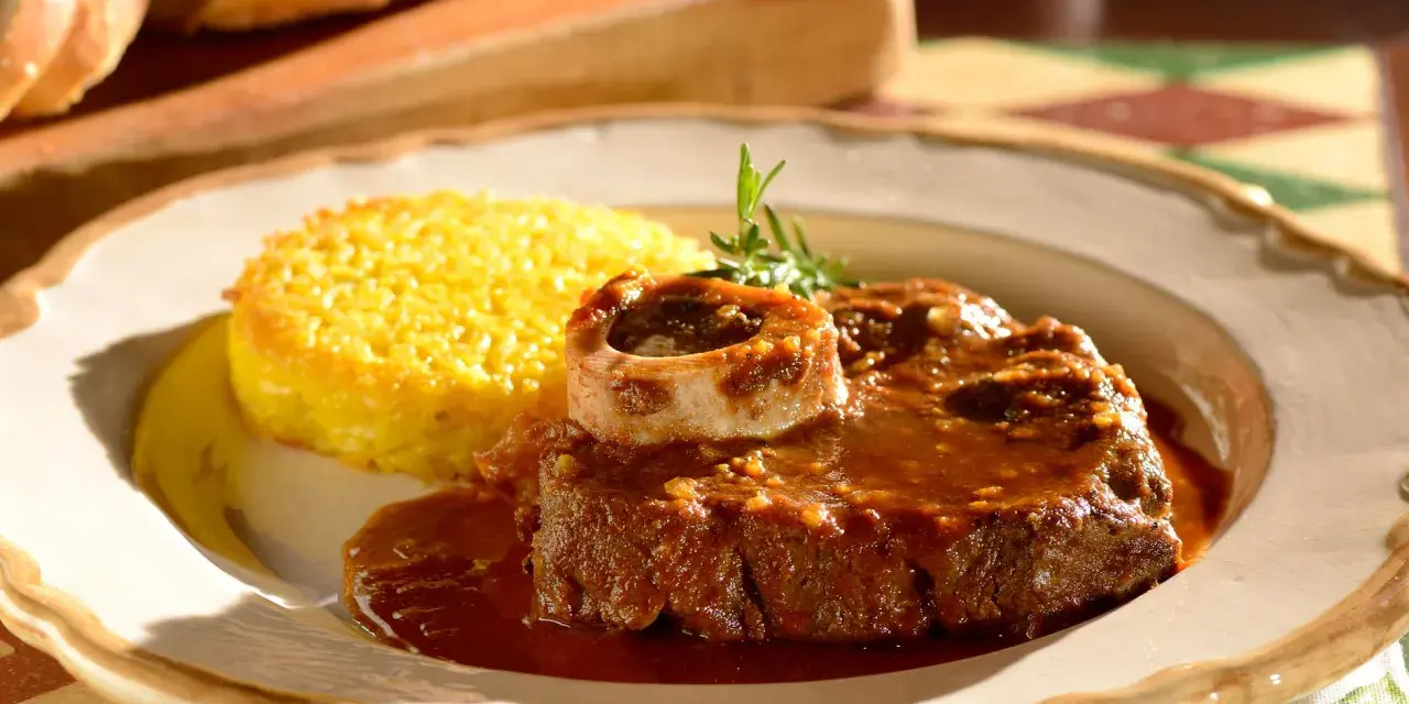Un succulento ossobuco alla milanese, cotto lentamente e servito con polenta gialla e un rametto di rosmarino.