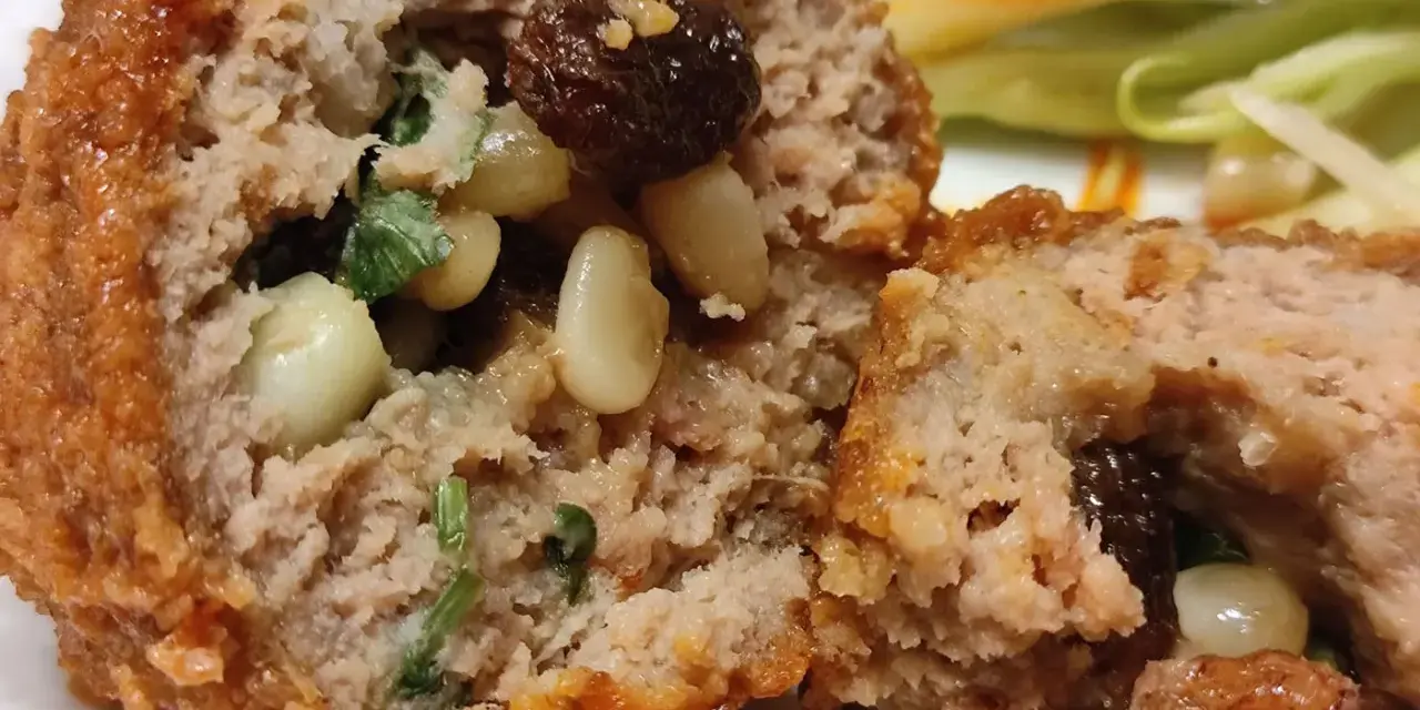 Polpette al sugo napoletane, un abbraccio di carne saporita con pinoli e uvetta, immerse in un sugo rosso invitante.