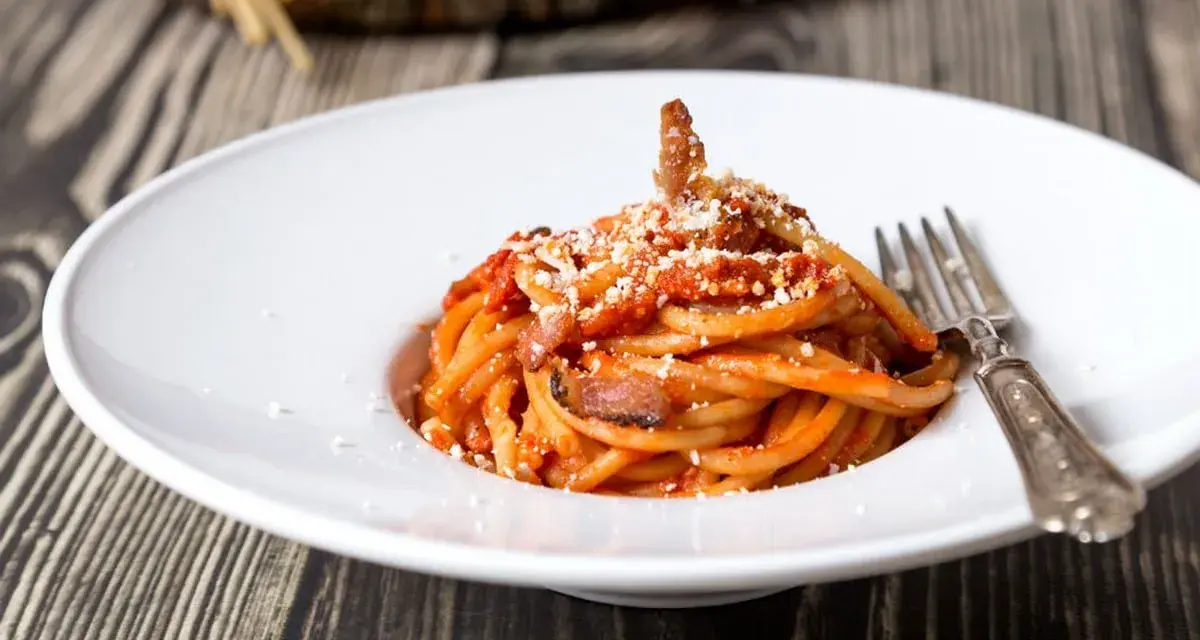 Piatto di spaghetti con sugo rosso, guanciale e formaggio grattugiato. Una gustosa ricetta originale amatriciana cipolla.