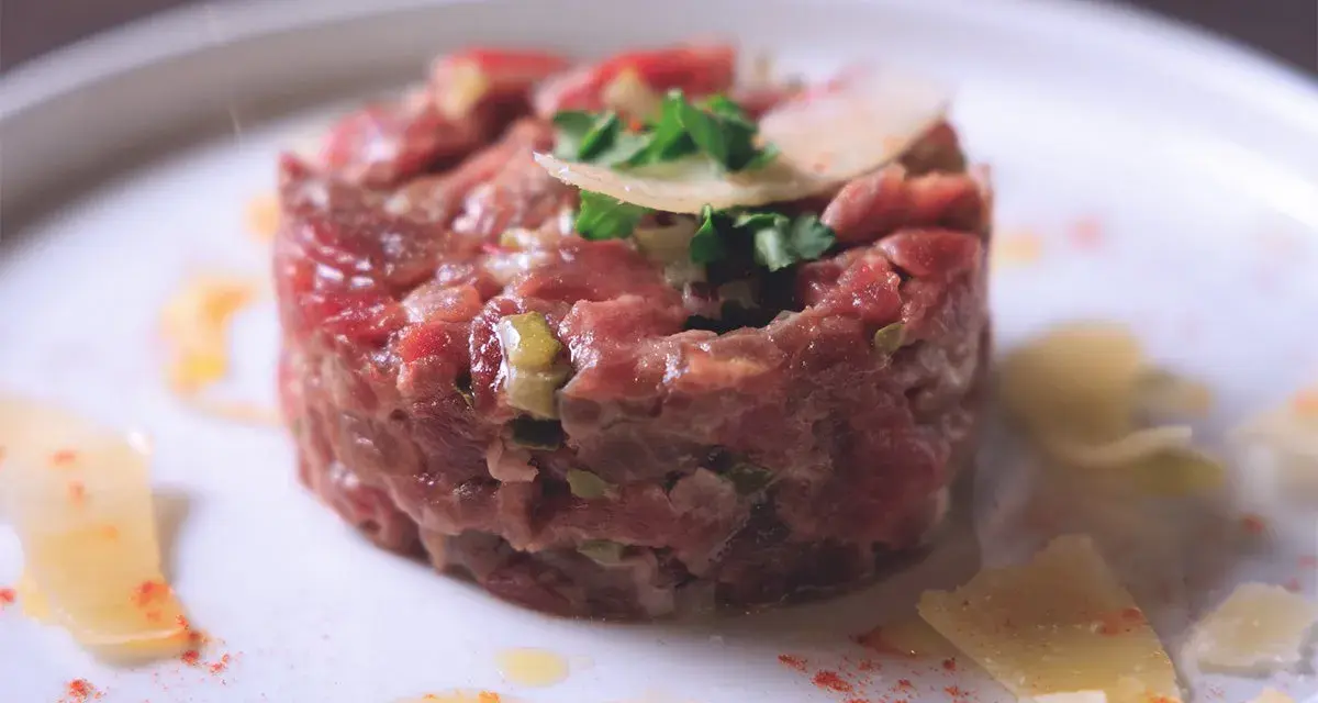 Tartare di manzo, un piatto raffinato. Scopri come condirla per un sapore indimenticabile, con scaglie di parmigiano e un tocco di paprika.