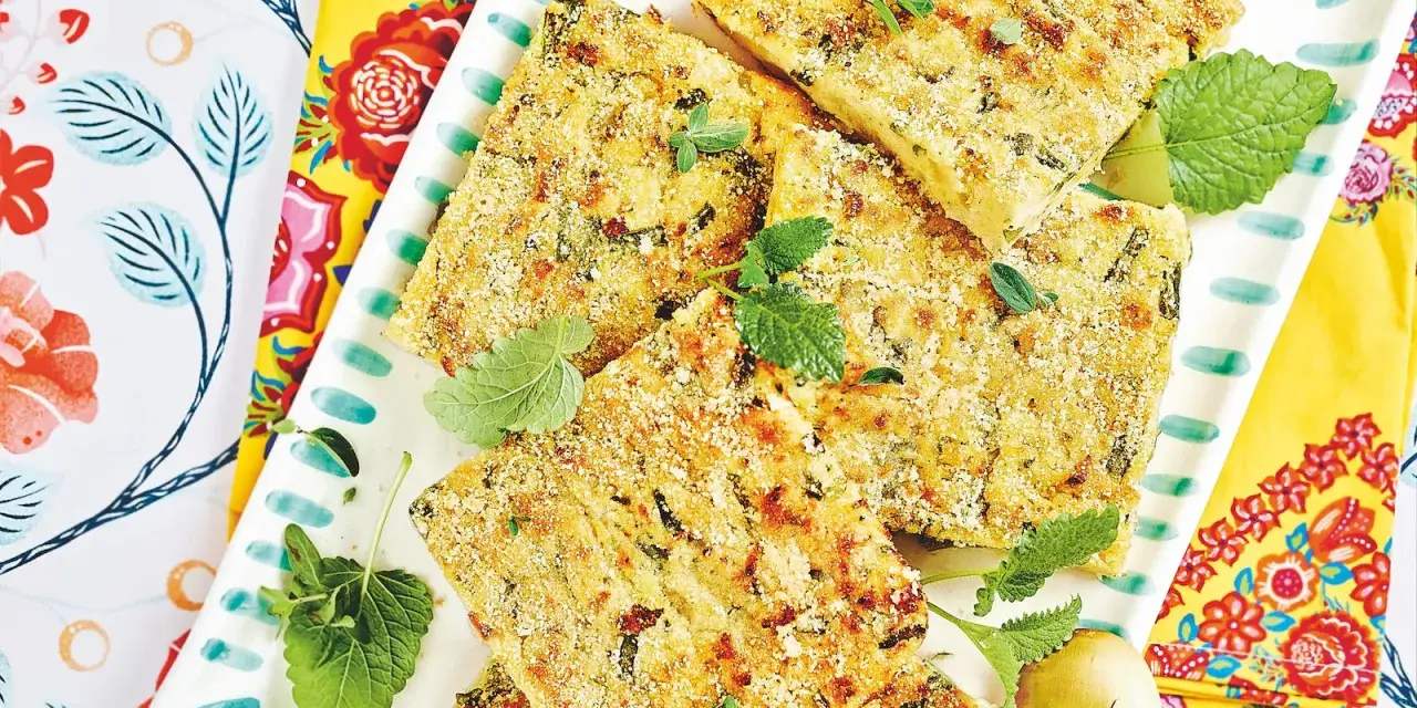 Fette dorate di polpettone di fagiolini, guarnite con erbe aromatiche fresche, su un piatto decorato con motivi floreali vivaci.