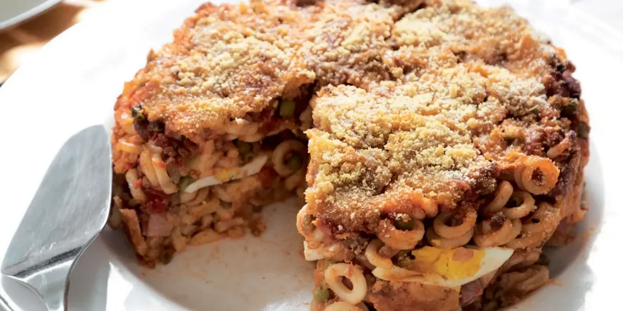 Un invitante anelletti al forno, dorato e croccante, con strati di pasta, ragù, piselli e uova sode.