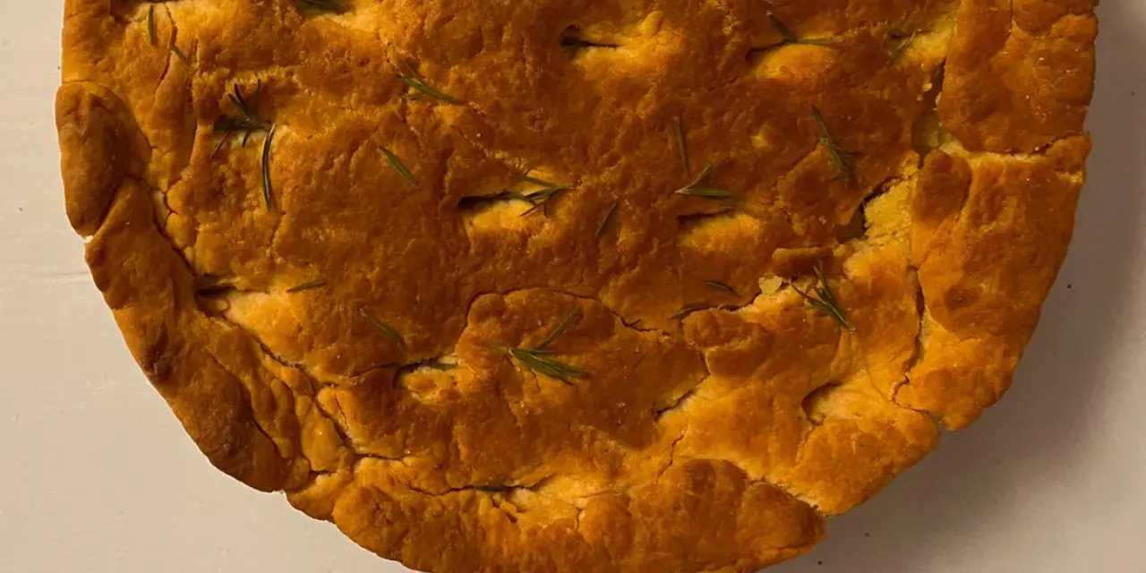 Focaccia di lenticchie dorata e fragrante, con rosmarino fresco che spunta dalla crosta croccante.