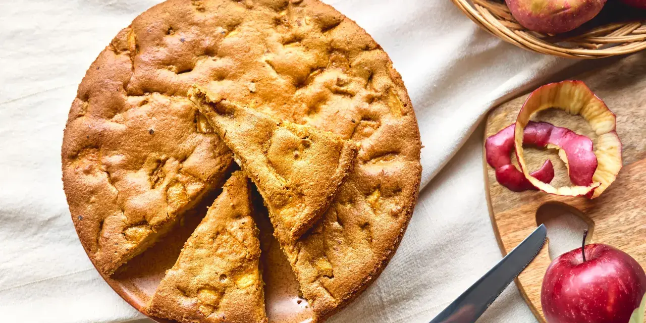 Una deliziosa torta di mele con farina di avena, appena sfornata, con mele fresche e scorze su un tagliere.