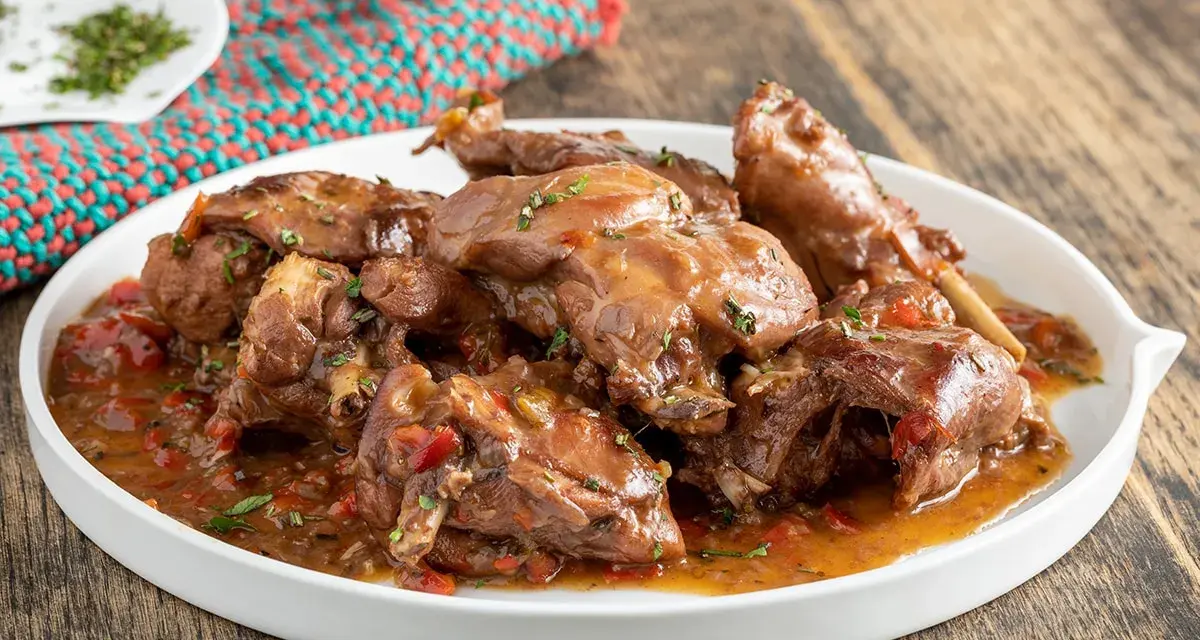 Piatto di coniglio con peperoni rossi e verdi, cotto in umido con erbe aromatiche.