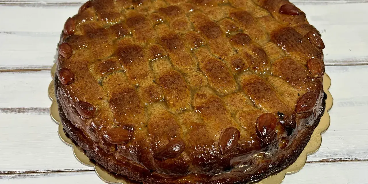 Deliziosa torta di mandorle siciliana, con una crosta dorata e mandorle intere a decorare il bordo.