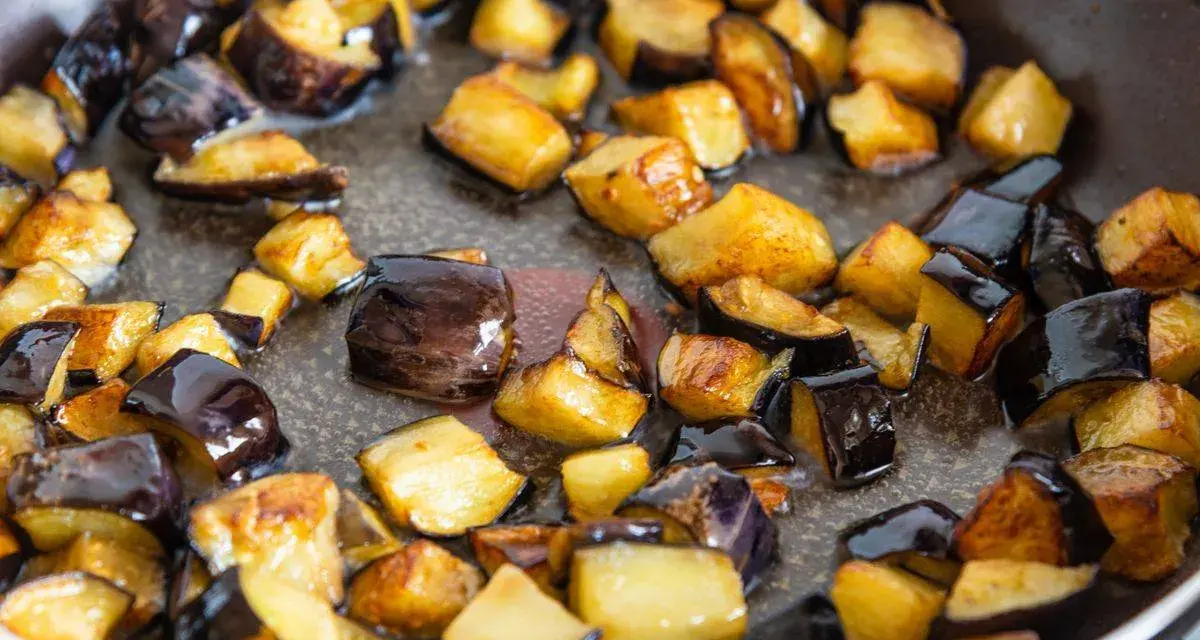 Melanzane a cubetti dorate e caramellate in padella, pronte per uno dei 100 modi per cucinare le melanzane.