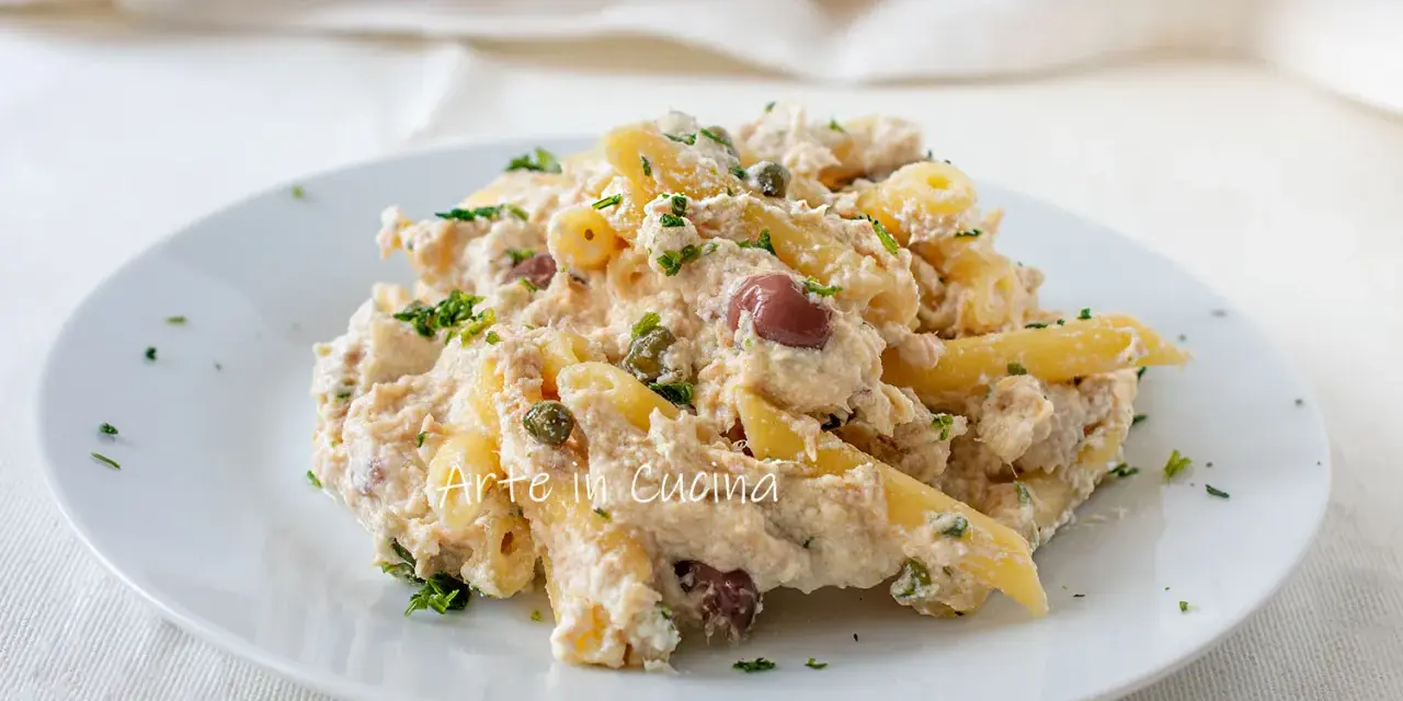 Piatto di pasta cremosa con tonno, capperi e olive taggiasche, guarnito con prezzemolo fresco.