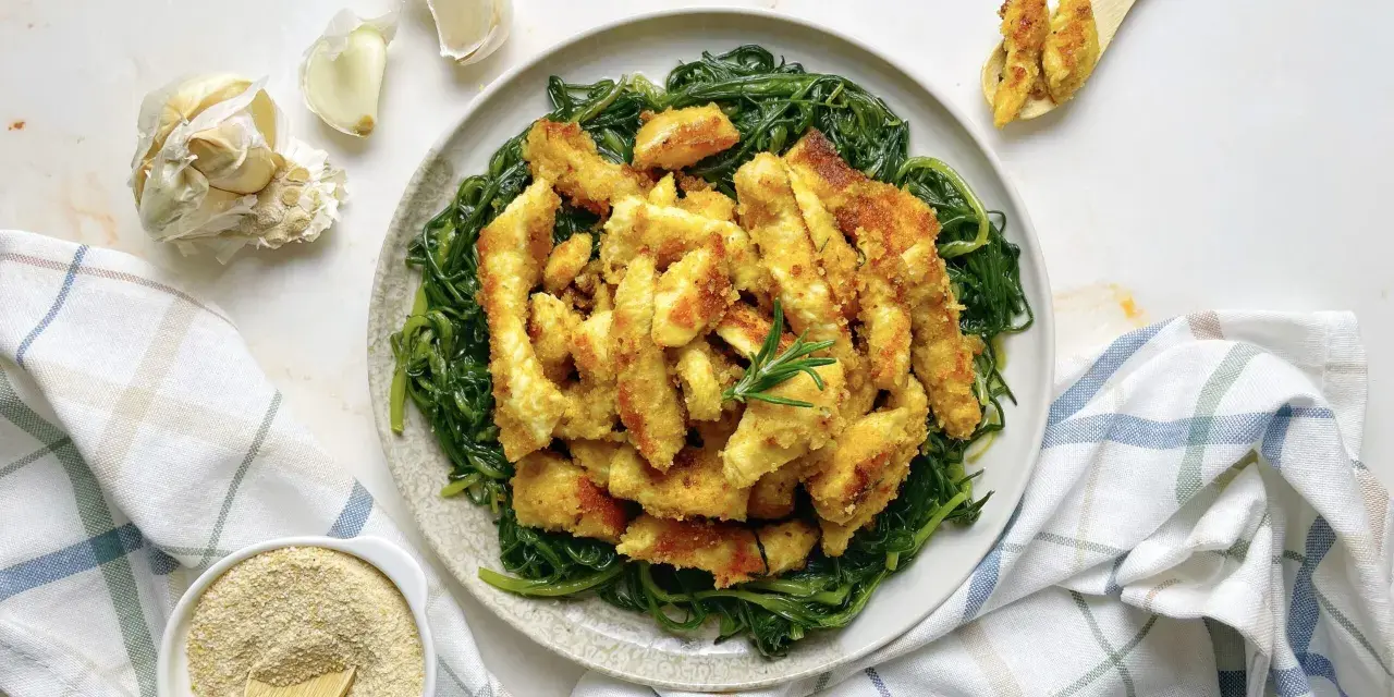 Luganega al forno croccante su letto di verdure verdi. Accanto, aglio e pangrattato.