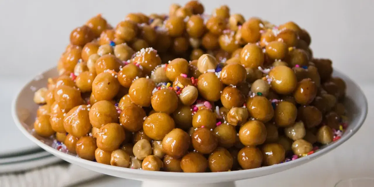 Struffoli ricetta della nonna: palline dorate e lucide, cosparse di zuccherini colorati, un dolce tradizionale che profuma di casa.