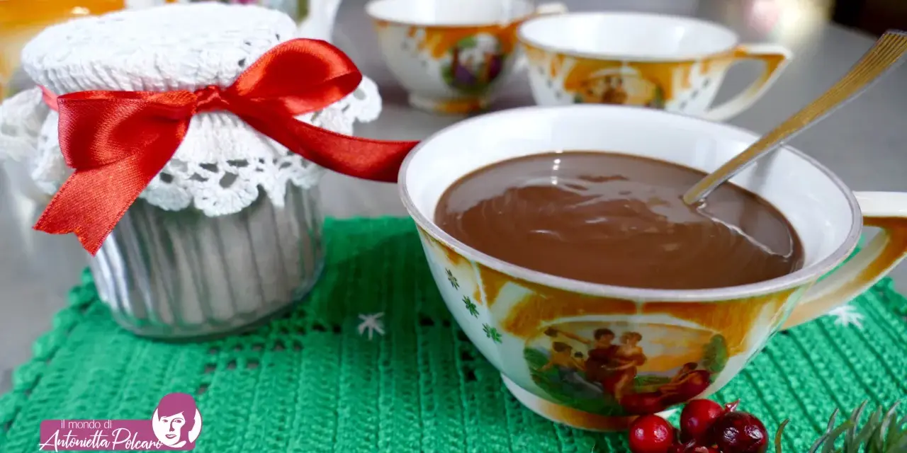 Un vasetto decorato con un fiocco rosso e una tazza piena di cioccolata fatta in casa, pronta per essere gustata.