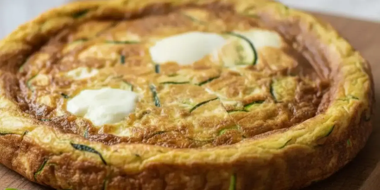 Frittata con mozzarella al forno, dorata e soffice, con zucchine a rondelle e ciuffi di mozzarella filante. Un piatto gustoso e leggero.