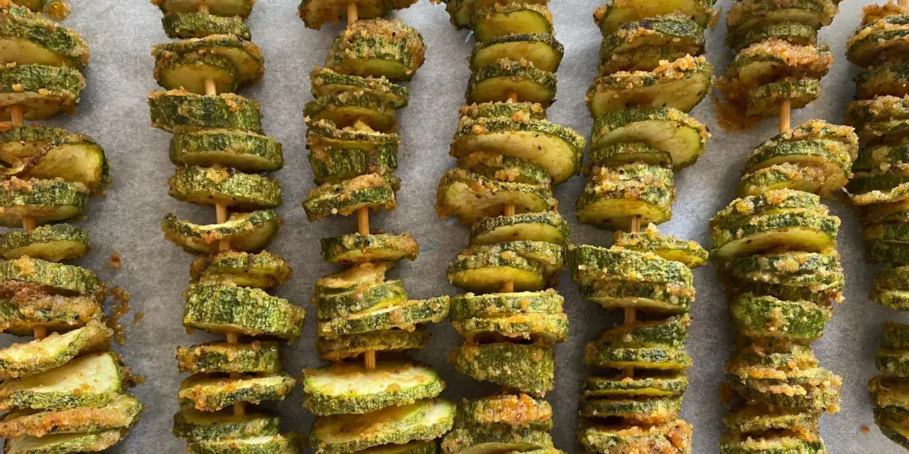 Spiedini di zucchine al forno, dorati e croccanti, pronti per essere gustati.